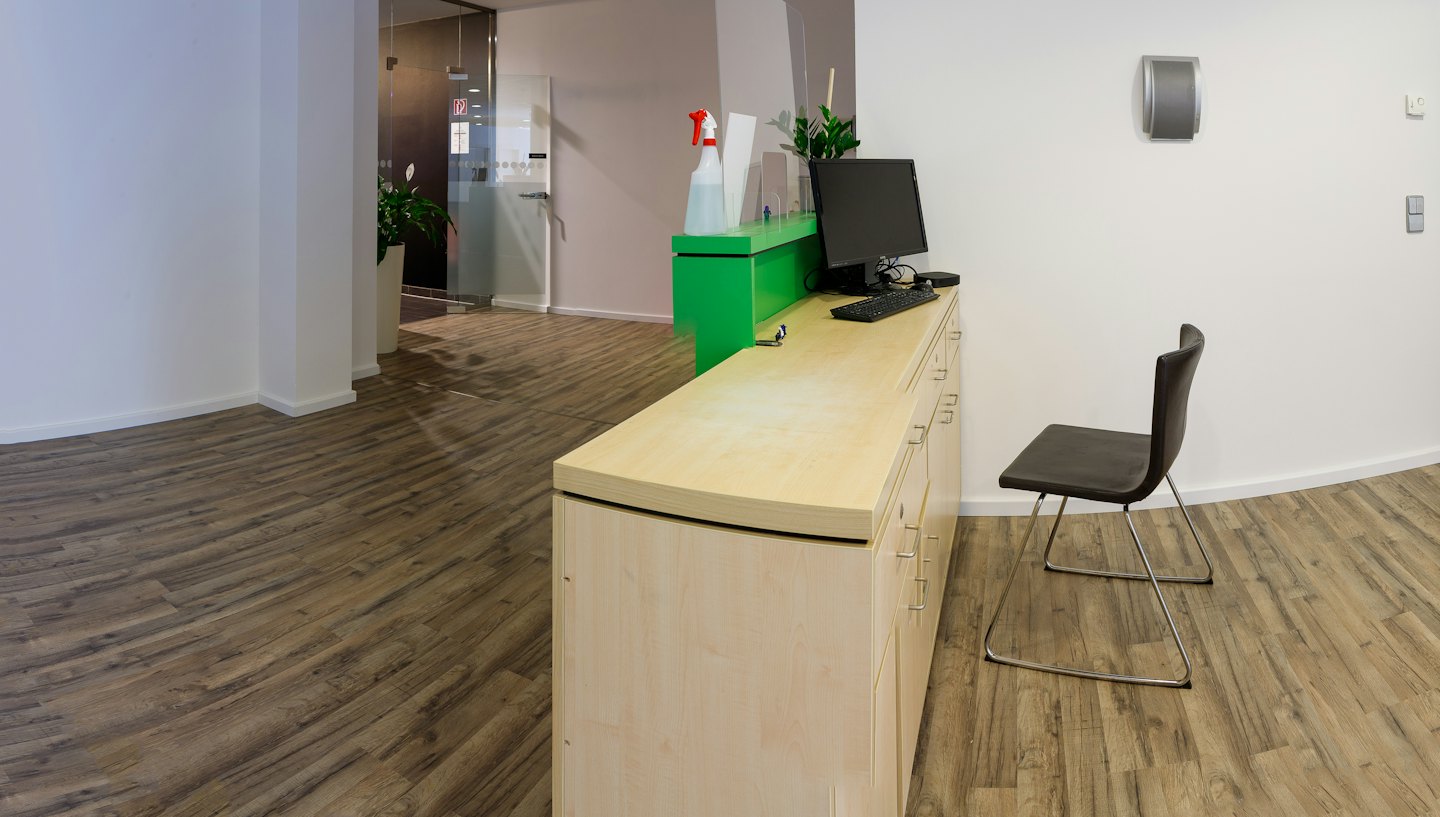 Scrivania moderna di reception di un ufficio con computer e divisori protettivi.